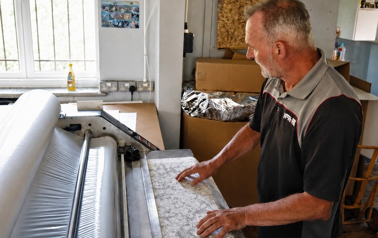 Aqua3 map being hand-fed through the laminator
